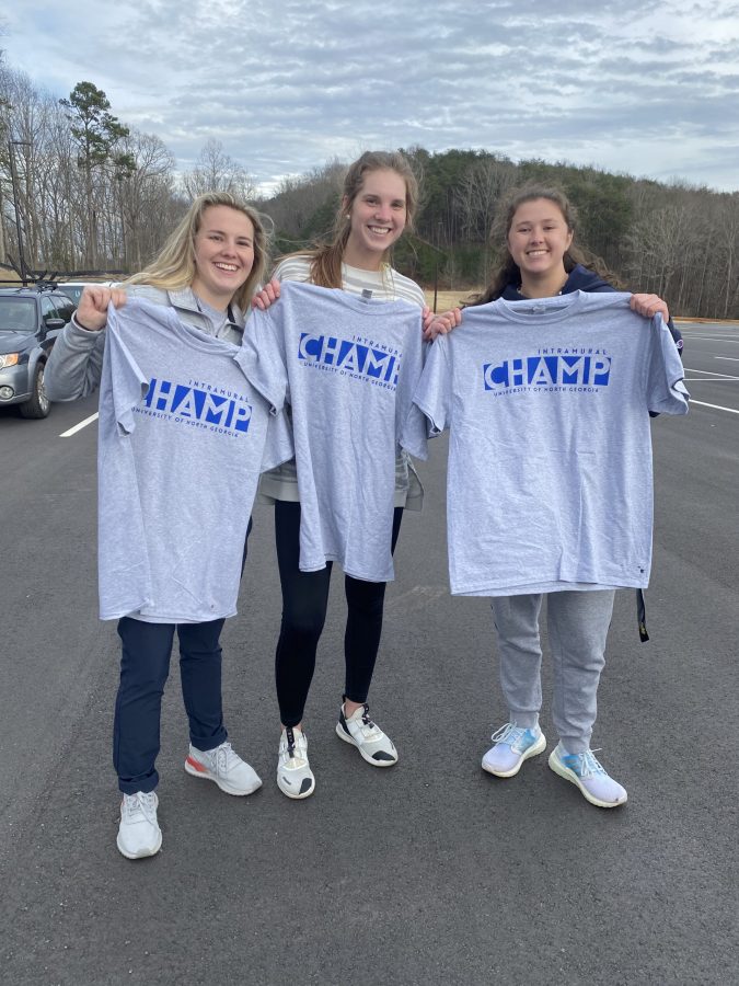 Katelyn Lee, Emily Austin, and Leda Tidwell of Alpha Gamma Delta hold up their Champ shirts after winning the Spikeball championship in Phase 1 
