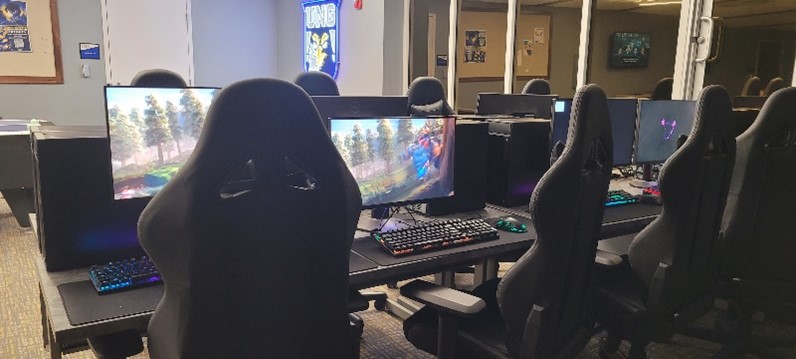 PCs with games on screen, gaming chairs. 