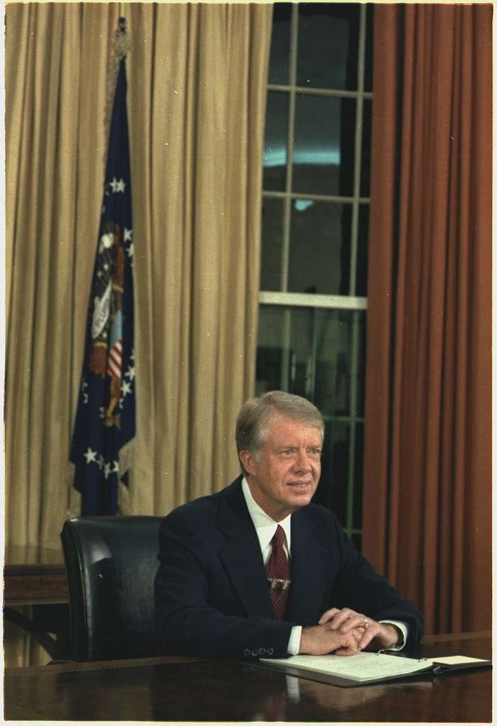 Former President Jimmy Carter sits at the Resolute Desk in the Oval Office. 