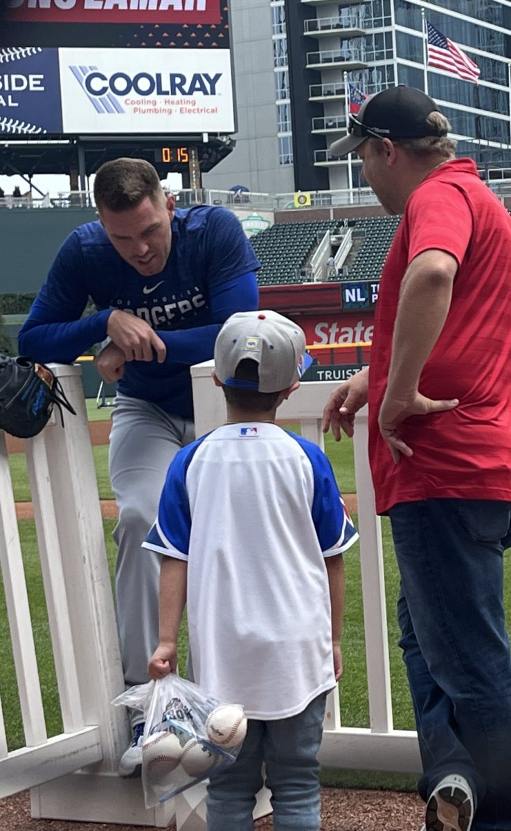 Freddie Freeman, the Dodgers' hero in Game One of the 2024 World Series, chats to Braves broadcaster Kevin McAlpin and his son before a game in Atlanta in 2023.